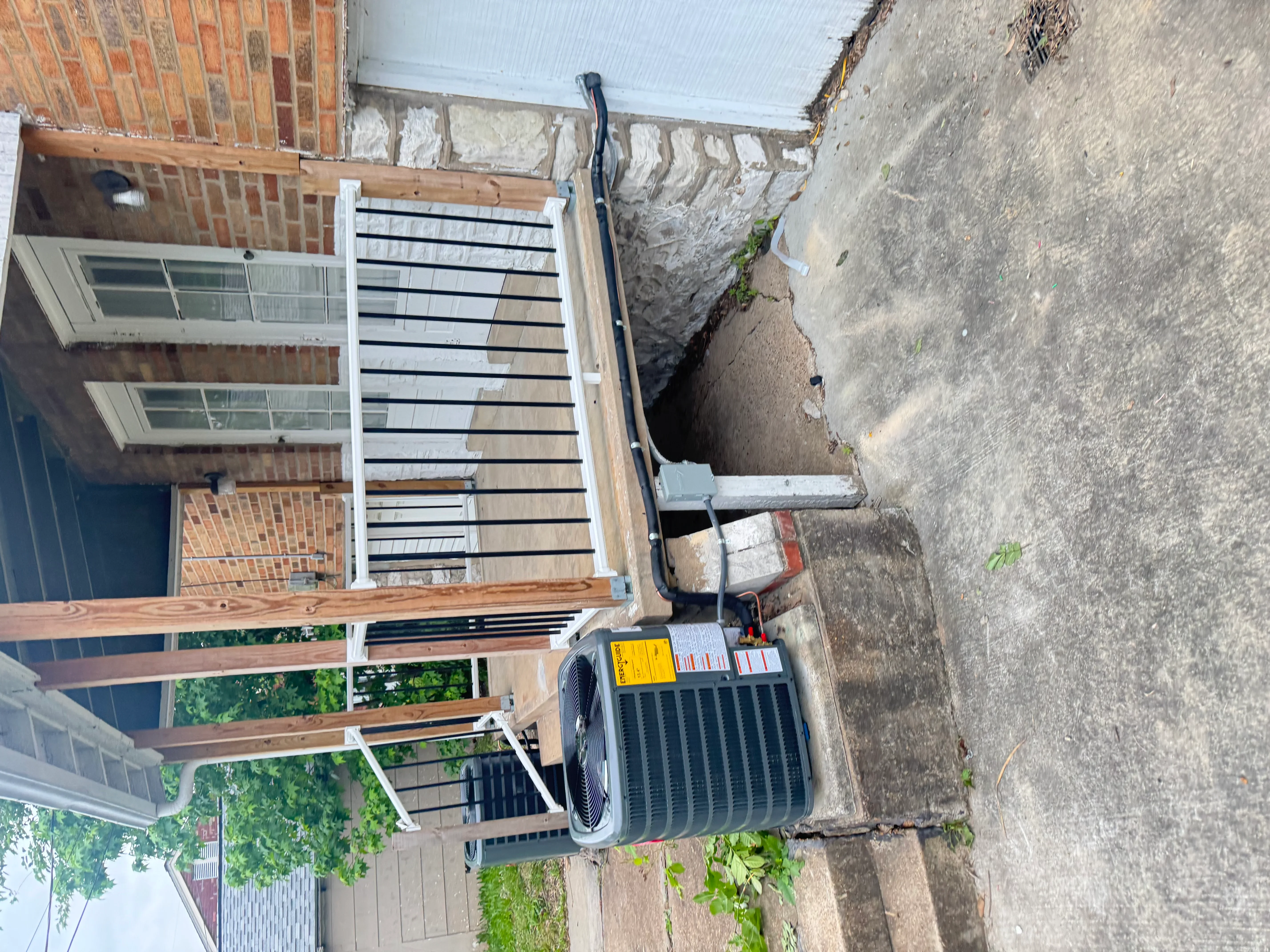 New AC condenser unit installed on concrete pad with refrigerant lines and electrical connections